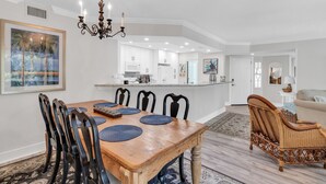 Un coin repas avec une table en bois, des chaises noires et un lustre.