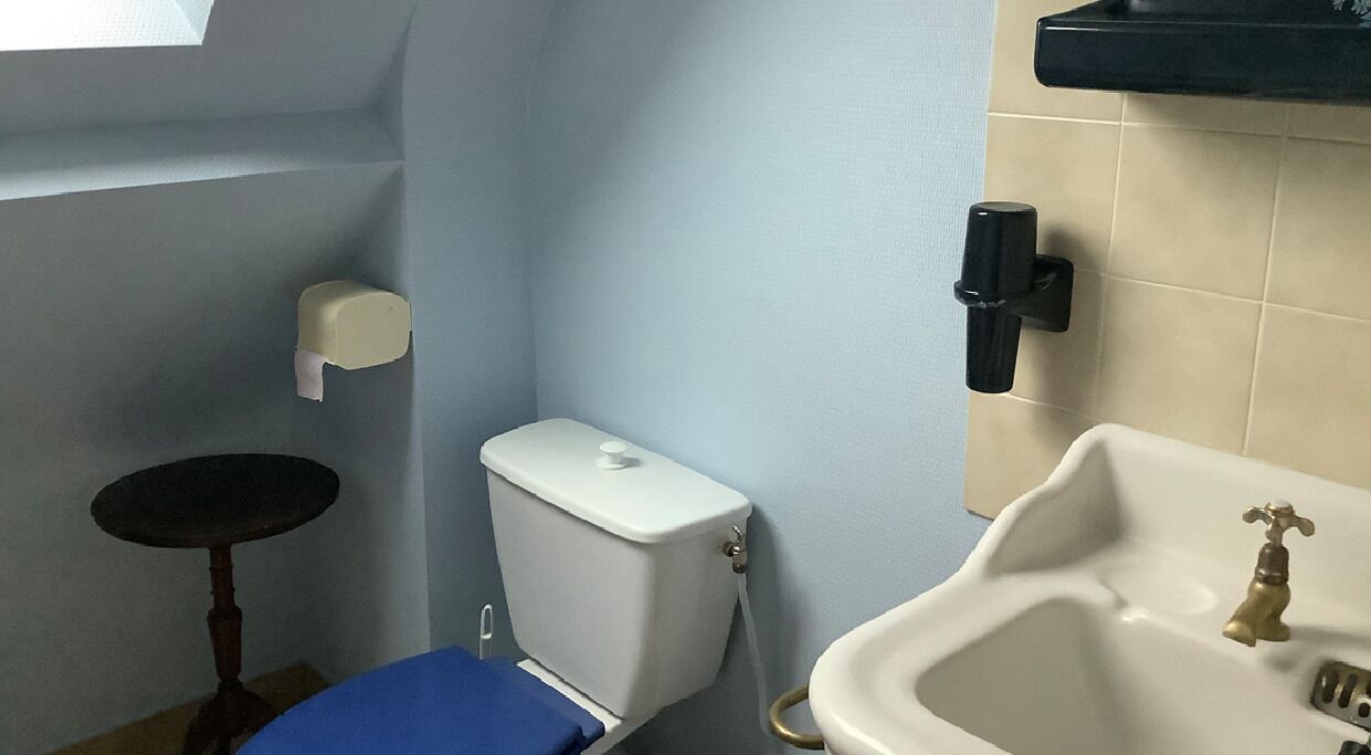 A small bathroom with a toilet, sink, and a small table.