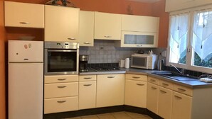 A kitchen with white cabinets, a refrigerator, an oven, a microwave, and a sink.