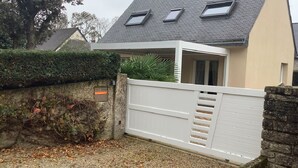 A gated entrance to a house with a sloped roof and a small porch.