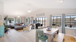 A spacious living area with a large sectional sofa, a dining table with chairs, and a view of a lake through large windows. - Lakefront 4bd-2ba; Deep water; Large Porch; Sleeps 14; Pet friendly (Macon)