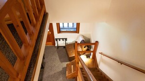 A staircase with wooden railings leading to a landing. A small table and a chair are on the landing. - Birch Room 10 - loft room at The Inn At Mazama (Mazama)