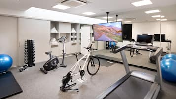 A modern gym with a treadmill, stationary bike, and exercise balls.