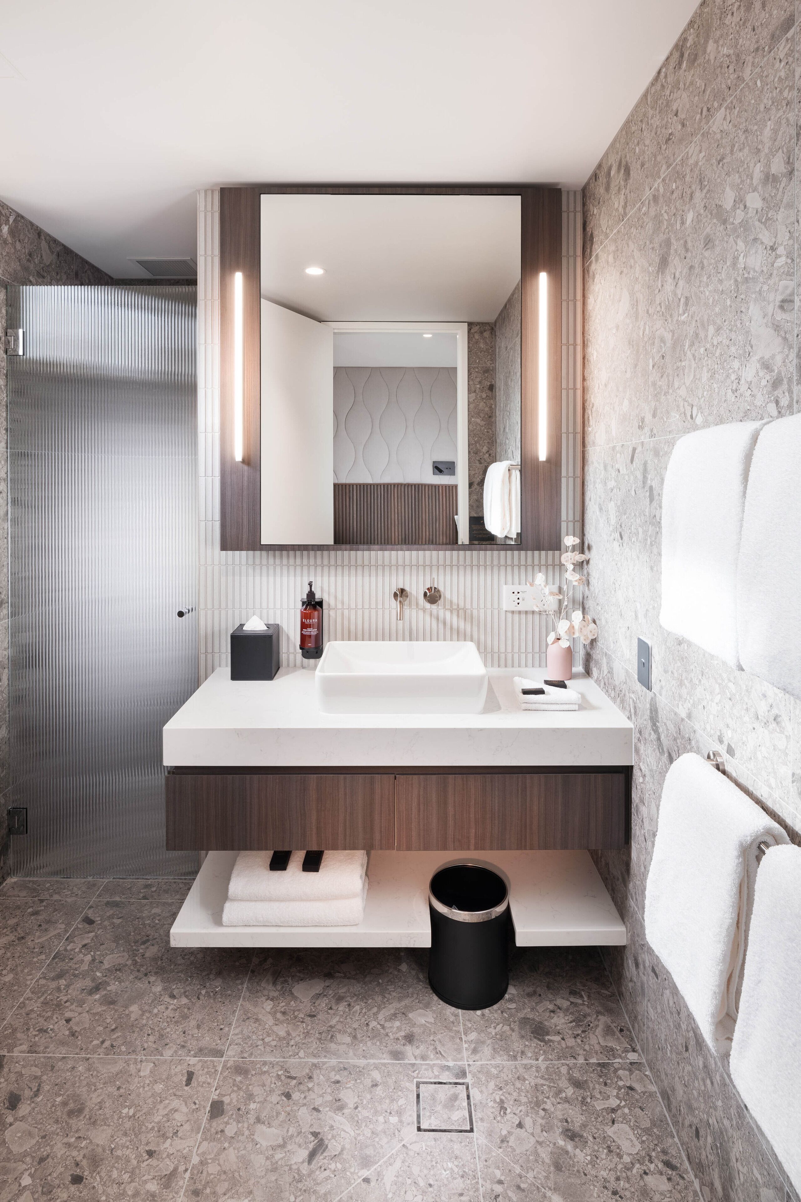 A modern bathroom with a white sink, a mirror, and a towel rack.