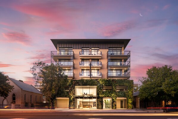 A multi-story hotel with a modern design, featuring balconies on each floor, a prominent entrance with a glass facade, and a lush green wall at the base. - Majestic M Suites (North Adelaide)