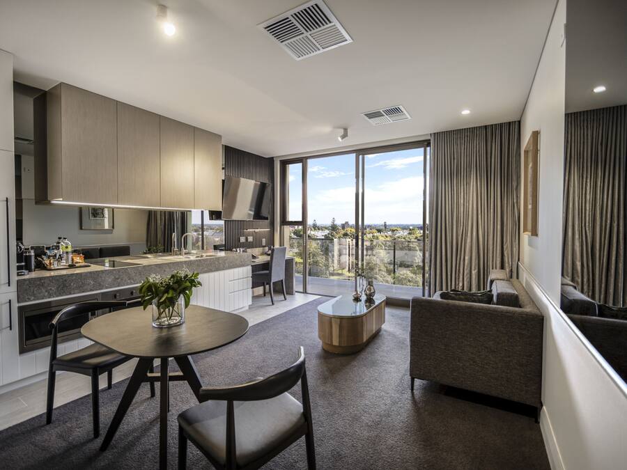 A modern kitchen with a dining area, large windows, and a view of the city.