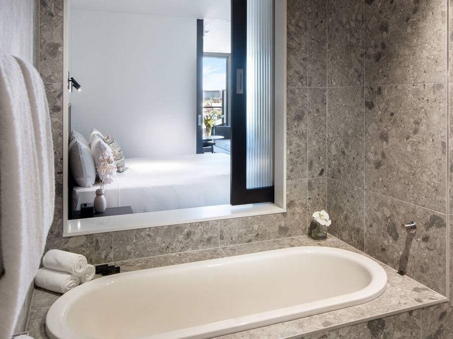 Une salle de bain moderne avec une baignoire sur pieds, un grand miroir et un mur recouvert de carreaux de marbre.