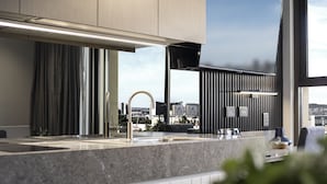 A modern kitchen with a granite countertop, stainless steel appliances, and a view of the cityscape through large windows. - Majestic M Suites (North Adelaide)