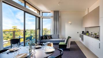 A modern kitchen with a dining area, large windows, and a view of the outdoors.