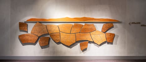A modern interior with a large abstract wooden art piece on the wall.