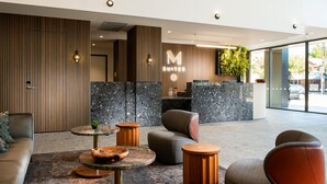 A modern hotel lobby with a reception desk, seating area, and large windows. - Majestic M Suites (North Adelaide)