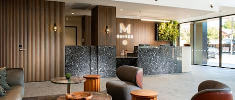 Un moderno vestíbulo de hotel con mostrador de recepción, zona de estar y grandes ventanales.