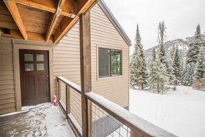 A wooden cabin with a balcony, a door, and a window.