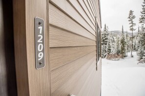 A wooden door with a metal plaque displaying the number 1209.