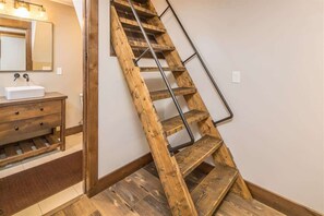 A wooden staircase with metal handrails in a room with a wooden vanity and a mirror.