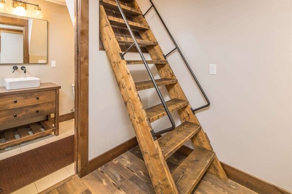 Una escalera de madera con barandillas de metal en una habitación con un tocador de madera y un espejo.