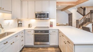 Eine moderne Küche mit weißen Schränken, Edelstahlgeräten und Holzboden.