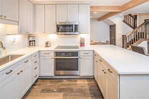 Eine moderne Küche mit weißen Schränken, Edelstahlgeräten und Holzboden.