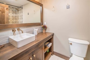 Een badkamer met een witte wastafel, een houten opbergmeubel en een toilet.
