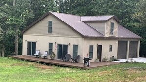 A two-story building with a porch, outdoor seating, and a garage. - "NEWLY BUILT" 3 Bedroom /2Bath House on the Lake (Benton)