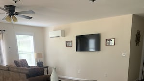 A dining area with a table and bench, a ceiling fan, a TV mounted on the wall, and a window with blinds. - "NEWLY BUILT" 3 Bedroom /2Bath House on the Lake (Benton)
