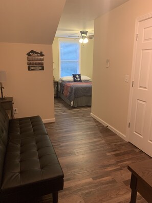 Relax in this cozy space with a comfortable bed, sofa, and ceiling fan.