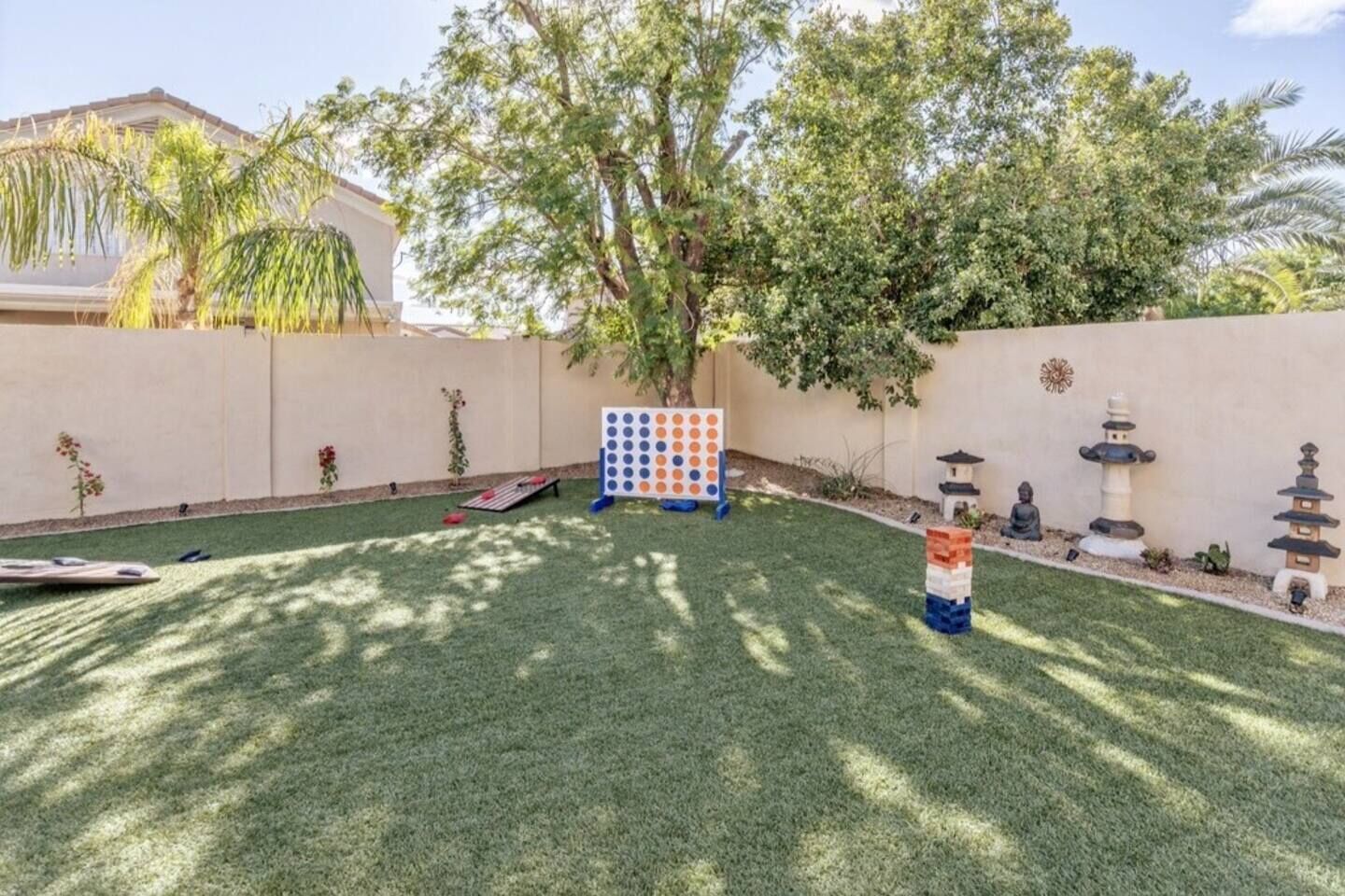 A backyard with artificial grass, a board game, and decorative statues.