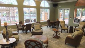 A spacious indoor area with multiple seating arrangements, large windows, and a view of the outside. - Ref 432. Stunning Villa at Bella Vida Resort near Disney. (Kissimmee)