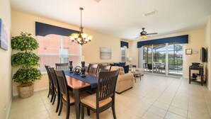 A spacious living area with a dining table, chairs, a sofa, and a ceiling fan. - Ref 432. Stunning Villa at Bella Vida Resort near Disney. (Kissimmee)
