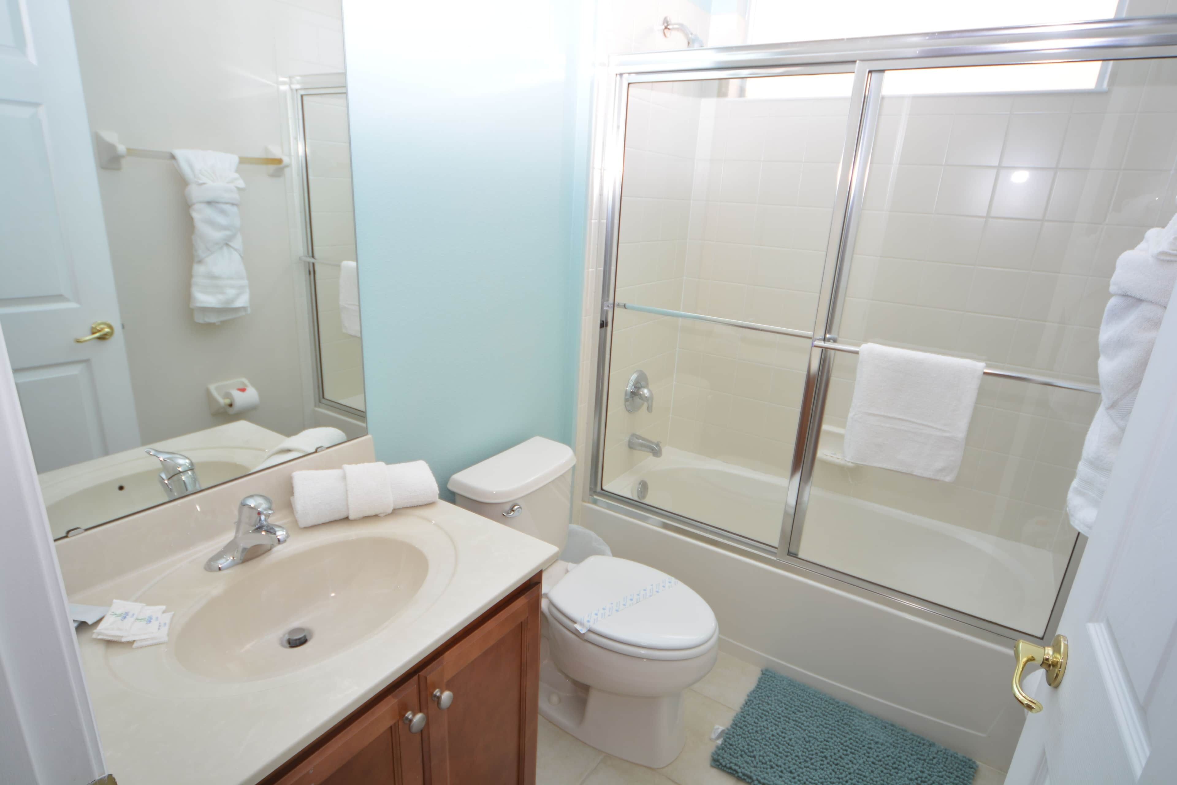 A bathroom with a sink, toilet, and glass-enclosed shower.