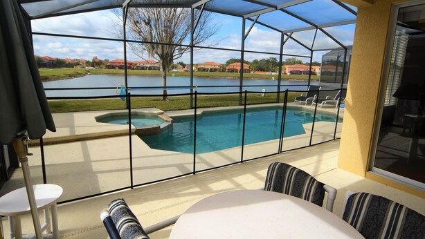 A covered patio with a pool, outdoor furniture, and a view of a lake and buildings. - Ref 432. Stunning Villa at Bella Vida Resort near Disney. (Kissimmee)