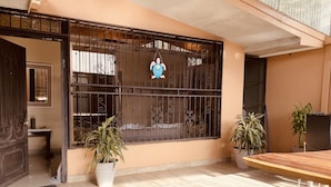 A room with a large window with decorative metal bars, a wooden table, two potted plants, and a tiled floor. - In the middle of the best beaches, private house with pool. (Tamarindo)