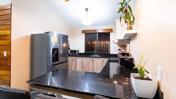 A modern kitchen with a large island, stainless steel appliances, and wooden cabinetry. - In the middle of the best beaches, private house with pool. (Tamarindo)