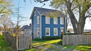 Une maison à deux étages, avec une façade bleue et des éléments décoratifs blancs.