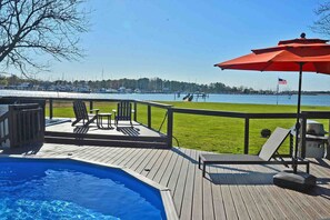 A wooden deck with a swimming pool, lounge chairs, and an American flag. - Waterfront w/private pier, pool, Hot Tub, kayaks and in town. (Rock Hall)