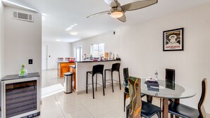 Une cuisine moderne avec un coin bar, une table à manger avec des chaises et un ventilateur de plafond.