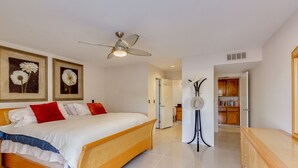 Une chambre à coucher avec un lit, un ventilateur de plafond et un couloir menant à une salle de bain et à un espace bureau.
