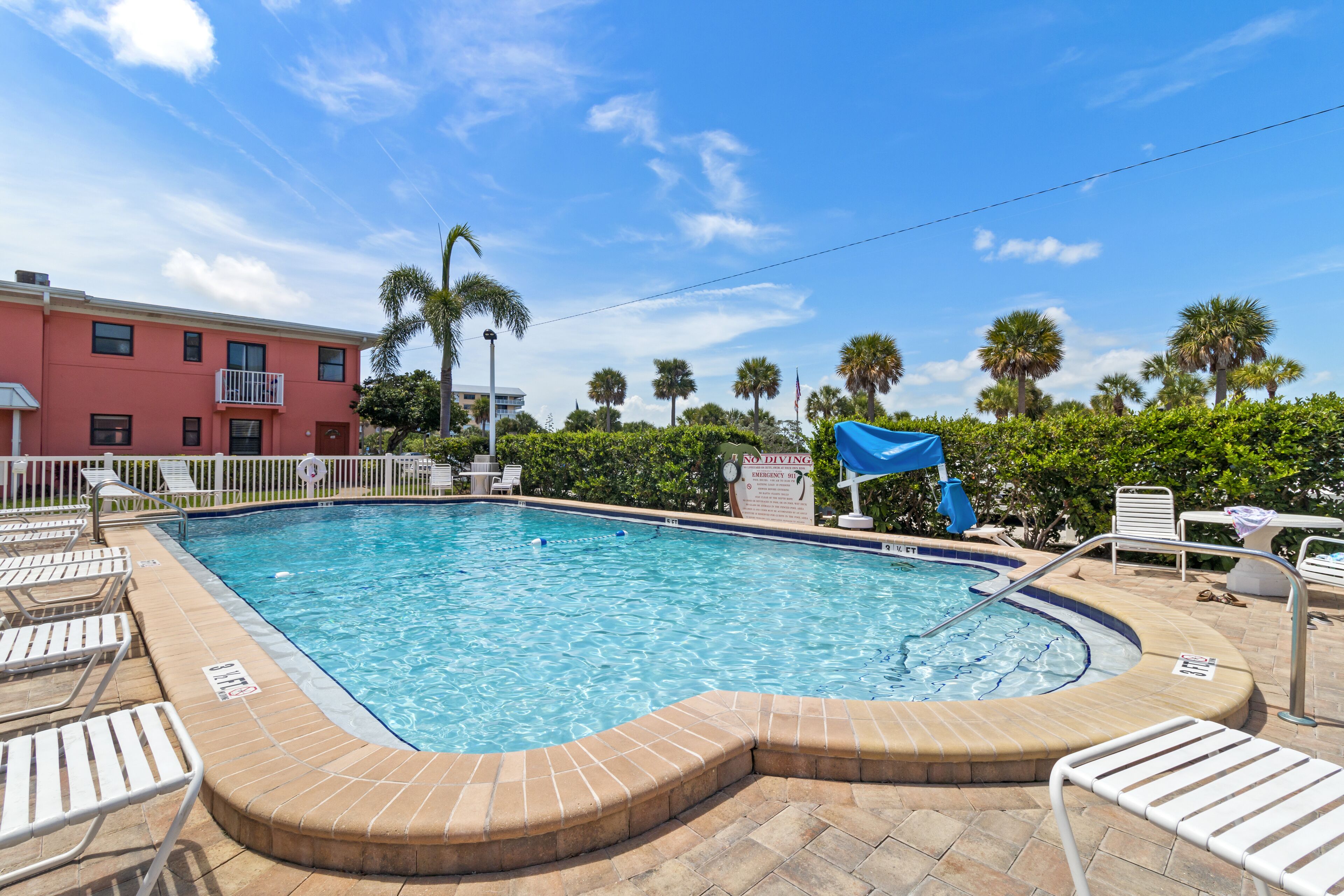 A swimming pool with a tiled deck, lounge chairs, and a 'No Diving' sign.