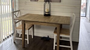 Un coin repas avec une table et des chaises en bois, un chandelier et une vue sur la plage par une fenêtre.