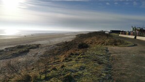 A coastal landscape with a sandy beach, grassy areas, and a fenced playground. - Captivatingly Stunning 2-bed Chalet in Bridlington (Bridlington)