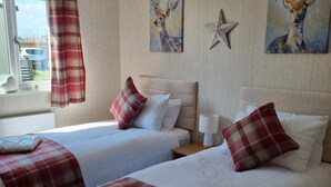 A hotel room with two beds, each with a red and white checkered blanket, white pillows, and a star decoration on the wall. - Captivatingly Stunning 2-bed Chalet in Bridlington (Bridlington)