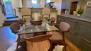 Una cocina moderna con una mesa de comedor de vidrio, sillas de madera y un tapete de cuero de vaca.