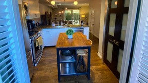 Una cocina moderna con una isla central, suelo de madera y vistas al salón.