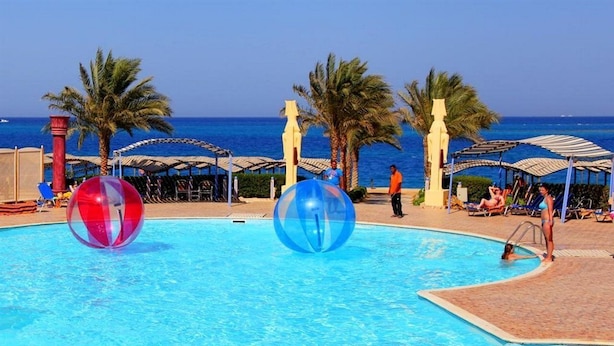 A swimming pool with two large transparent balls, palm trees, and beach umbrellas. - Sphinx Aqua Park Beach Resort (Hurghada)