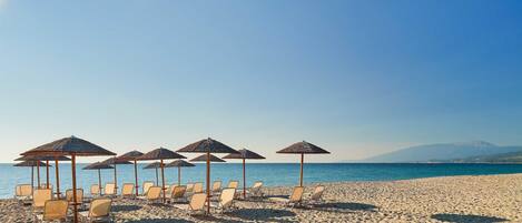 Aan een privéstrand, wit zand, ligstoelen, parasols
