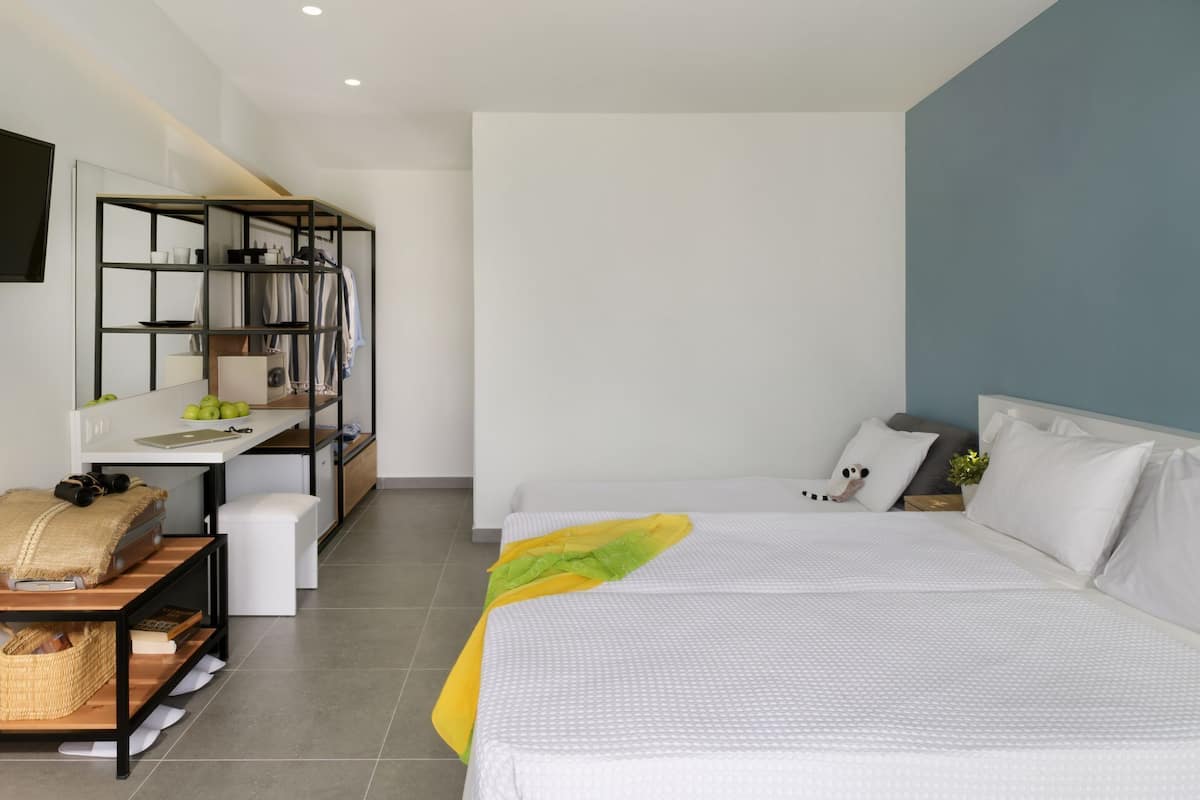 Une chambre moderne avec un grand lit, un bureau doté d’un miroir et une étagère.