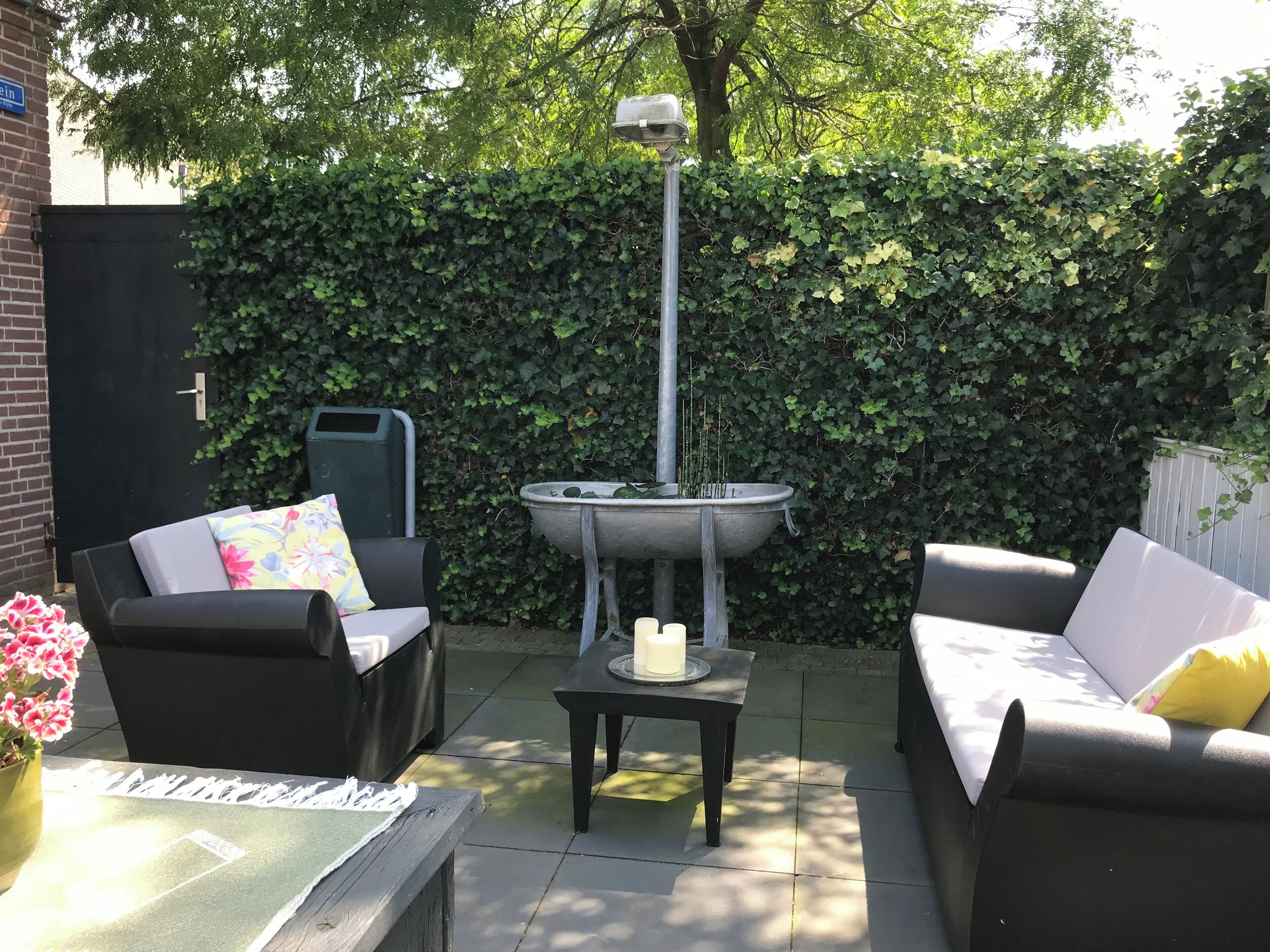 Un espace extérieur aménagé avec deux canapés, une table et une fontaine décorative.