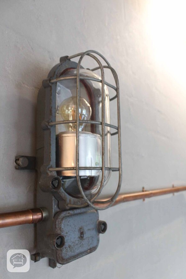 Una lámpara de pared de estilo vintage con cubierta de vidrio y cableado expuesto.