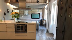 Una cocina moderna con microondas integrado, una isla grande con fregadero y un televisor montado en la pared.
