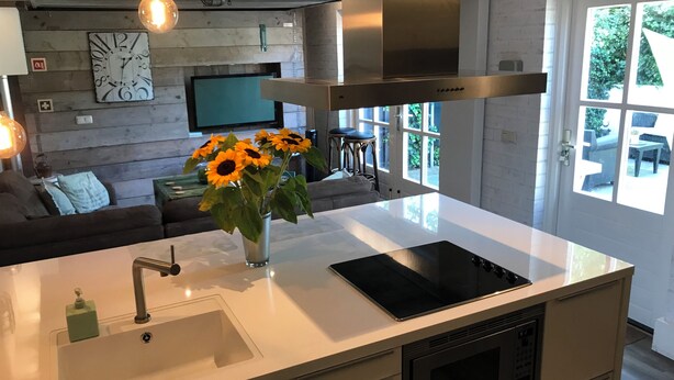 Una cocina moderna con una isla central, electrodomésticos de acero inoxidable y un amplio ventanal con vistas al exterior.